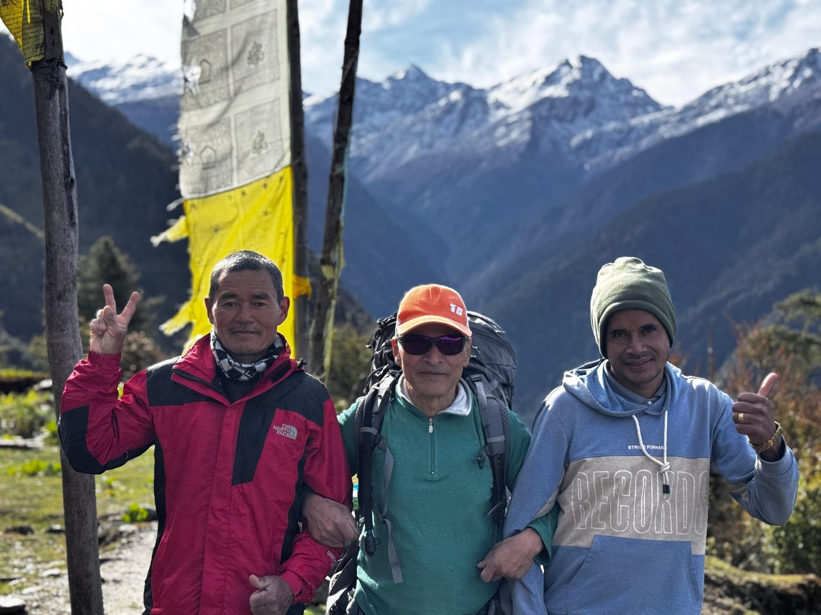 A guide and two trekkers with the range behind them